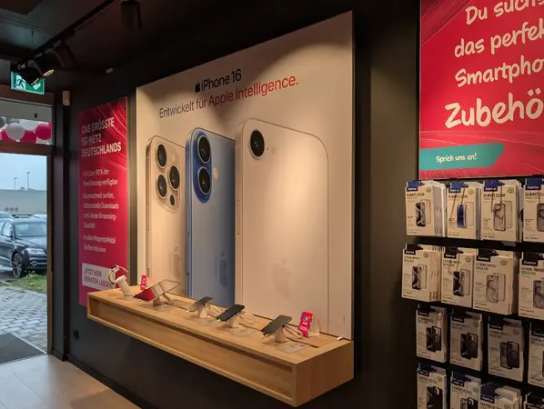 Apple iPhone 16 Ausstellung im Elektronikgeschäft mit Smartphone-Zubehör und Werbeplakaten.