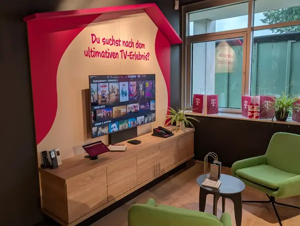 Modernes Wohnzimmer mit großem Smart-TV, Streaming-Dienst-Anzeige und Telekom-Dekoration.