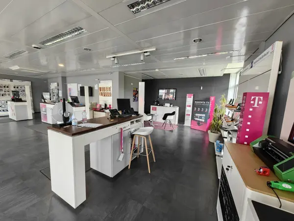 Modernes Telekom Shop-Innenraum mit Verkaufstresen, Technikprodukten und Beratungsecke.